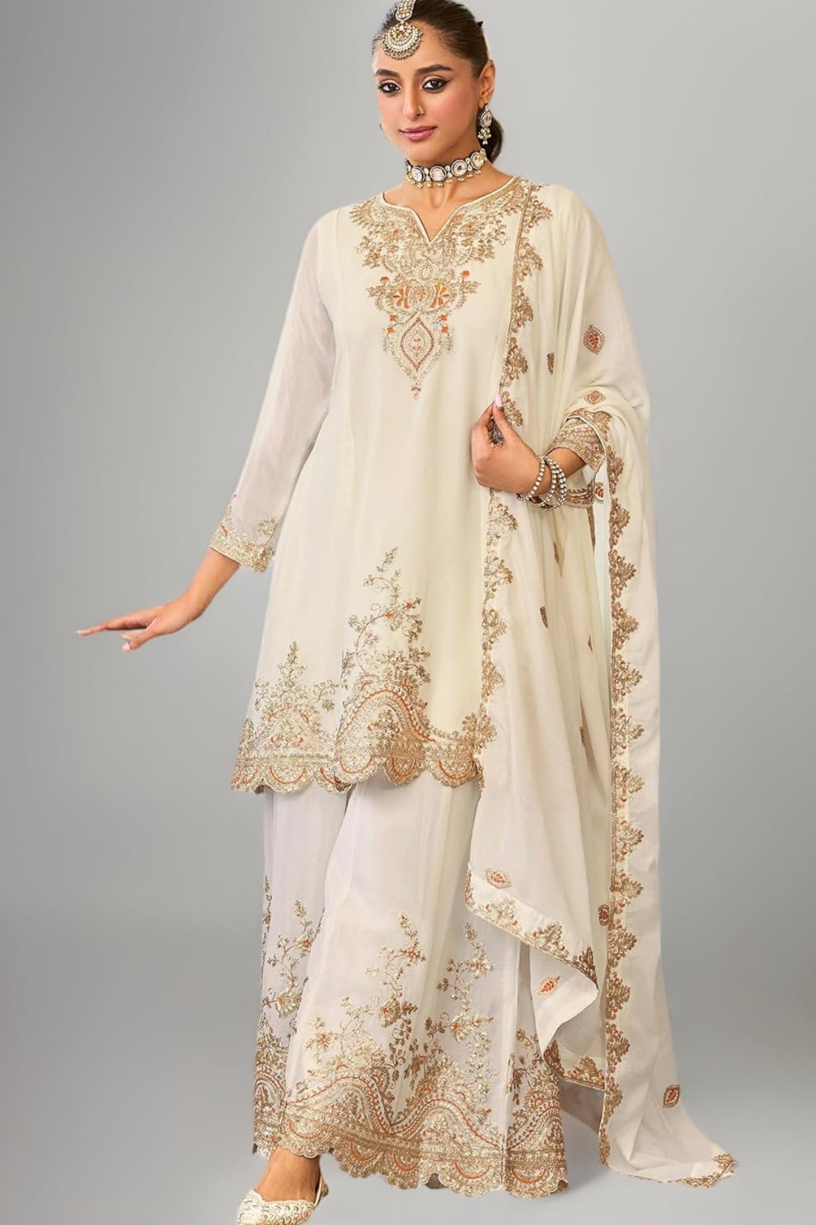 Woman wearing a cream-colored embroidered traditional outfit on a gray background