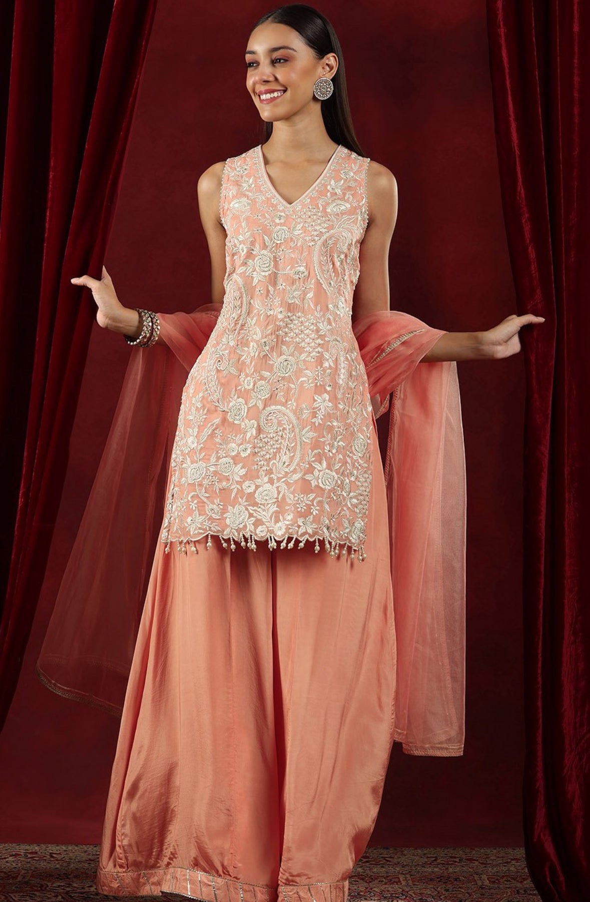 Bright pink ethnic Sharara outfit with heavy detailing and matching dupatta, suitable for traditional events.